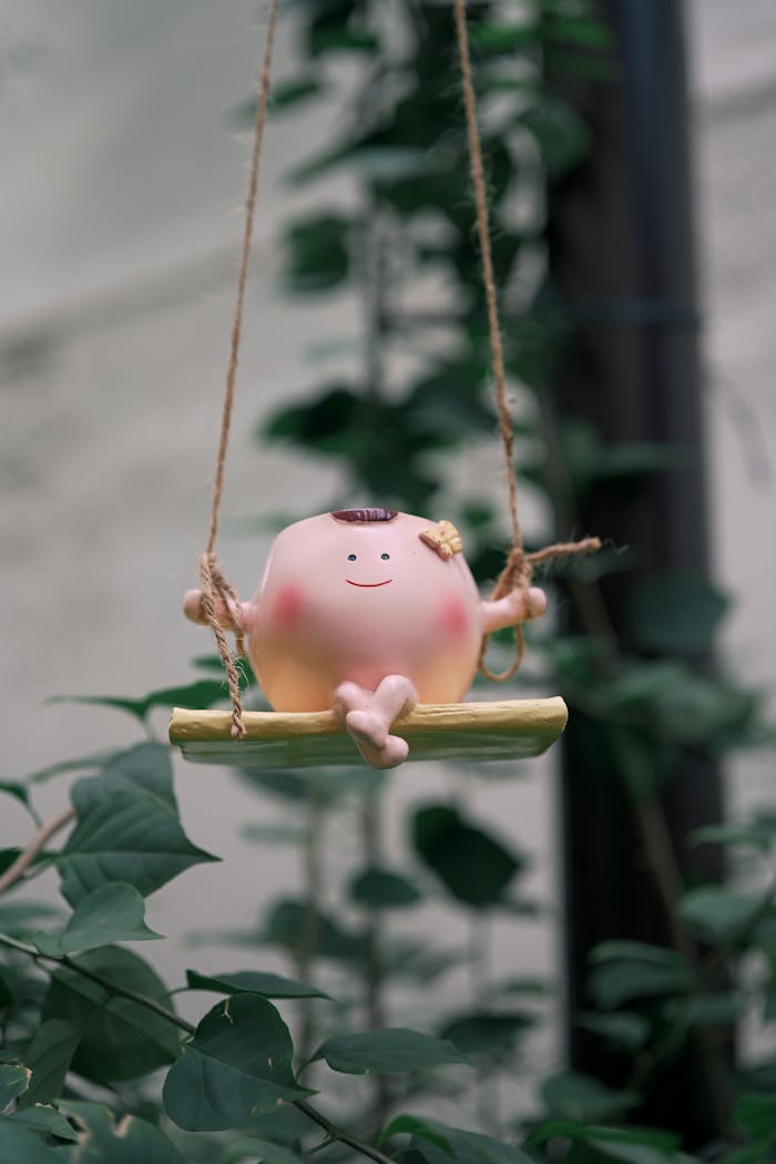 Home cute-figurine-on-swing-amidst-green-foliage-34264116